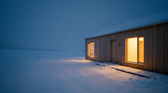 Maison individuelle de nuit en hiver, chaleur douce visible aux fenetres, symbole d'une isolation thermique efficace