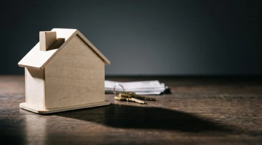 Illustration symbolique d'une maison miniature dont l'ombre portée se réduit progressivement, représentant la diminution de l'impôt sur la plus-value immobilière